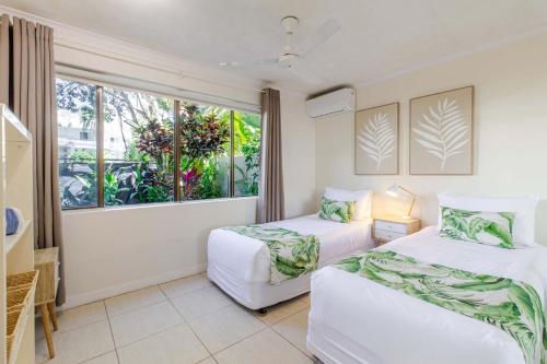 Dos camas en una habitación con ventana. en Sandy Toes, en Port Douglas