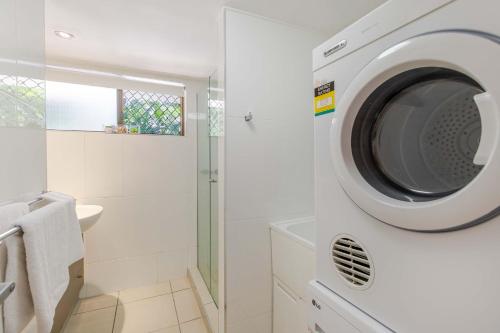 y baño con ducha y lavadora. en Sandy Toes, en Port Douglas