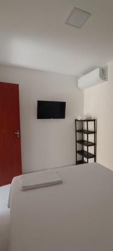 a white room with a bed and a tv on the wall at Pousada Brisa Rio in Aracaju