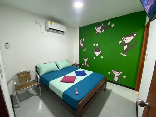 a small bedroom with a bed with a green wall at Fauna in Santa Marta