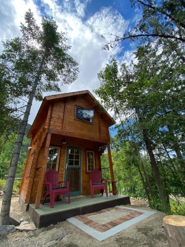 a tiny house in the woods with two purple chairs at Idyllic Cabin Retreat Only 5 Minutes Away From Nelson in Nelson