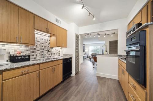 a large kitchen with wooden cabinets and black appliances at Spring Deals Walk to Galleria Holiday Ready Unit 108 in Houston
