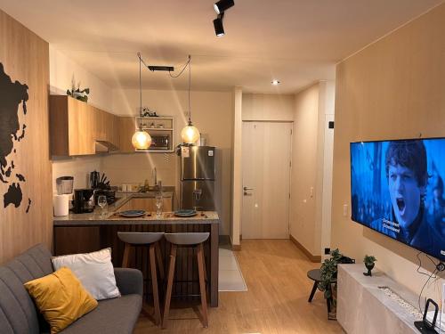 eine Küche und ein Wohnzimmer mit einem großen TV in der Unterkunft Tempo Moderno Departamento in San Antonio