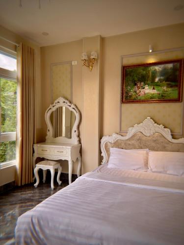 a bedroom with a bed and a mirror and a table at Hotel Nhà Mình in Da Lat
