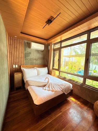a bedroom with a bed in a room with windows at Tagosilangan Beach House in Buruanga