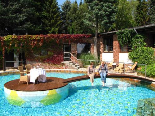 two women are walking in a swimming pool at Hotel Land Gut Höhne in Mettmann