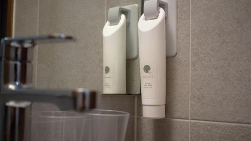 two white electric toothbrushes on a wall in a bathroom at Ramada by Wyndham Gumi in Gumi