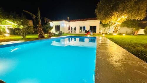 a swimming pool in front of a house at night at Luxury Villa with Pool & Garden5km from Cabo in Tetouan