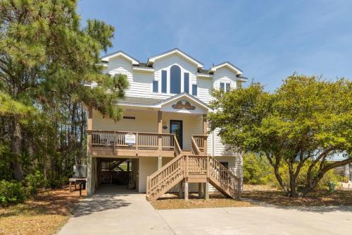 a house with a porch and a deck with trees at 1600 - 5 O`clock Somewhere in Corolla