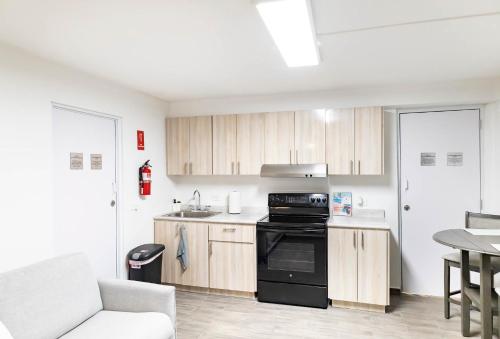 a kitchen with wooden cabinets and a black stove at AQUA Terrazas Studio 3 - Beachfront, Pool, Local Fun & Dining in Dorado