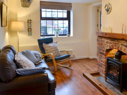 a living room with a couch and a fireplace at Ikkle Cottage in Blidworth