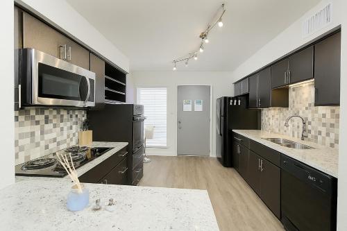 a large kitchen with black cabinets and a microwave at Perfect Location 2BR 5 Min Walk to Galleria Marquee Uptown in Houston
