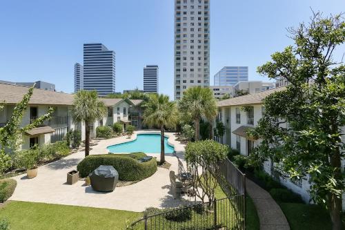 a courtyard with a pool and palm trees and buildings at Perfect Location 2BR 5 Min Walk to Galleria Marquee Uptown in Houston