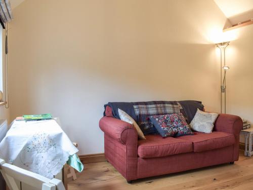 a red couch sitting in a living room next to a table at Gooses Roost - Uk32096 in Dorstone