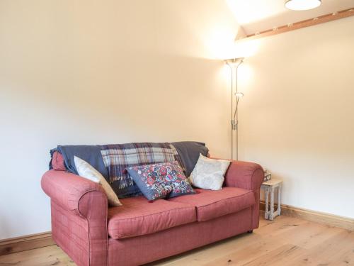 a red couch with pillows on it in a living room at Gooses Roost - Uk32096 in Dorstone