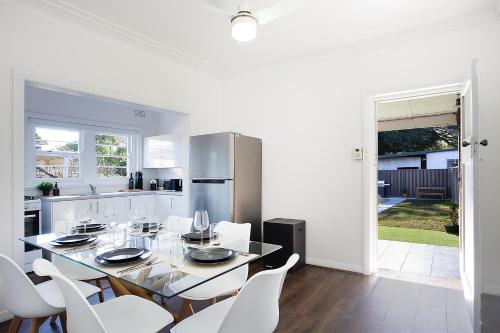 a white kitchen with a dining table and white chairs at 2RB Glebe Retreat Free Parking, Yard & Pet Friendly in Sydney