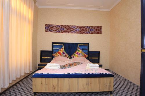 a bedroom with a wooden bed with pillows at JOMIY Guest House in Margilan