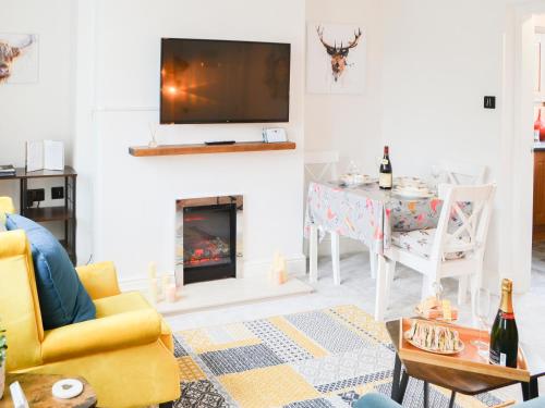 Wellwood Cottage في موربيث: غرفة معيشة مع موقد وتلفزيون على الحائط