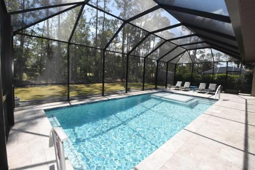 an indoor swimming pool in a glass house with a swimming poolvisor at Modern 3BR Retreat Heated Pool & Large Game Room in Bunnell