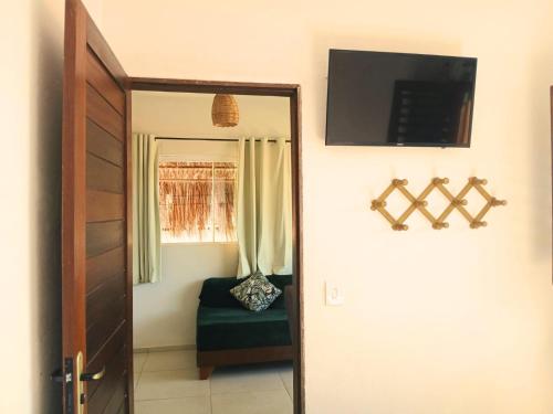 a door to a room with a chair and a television at 1 COCO BAMBÚ PIPA apto 1, a 200 m da praia e a 100 m do centro da cidade in Pipa