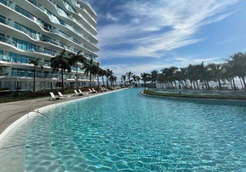 a swimming pool with chairs and a large building at Marítima Playa Flamingos Renting 5i Richards in Bucerías