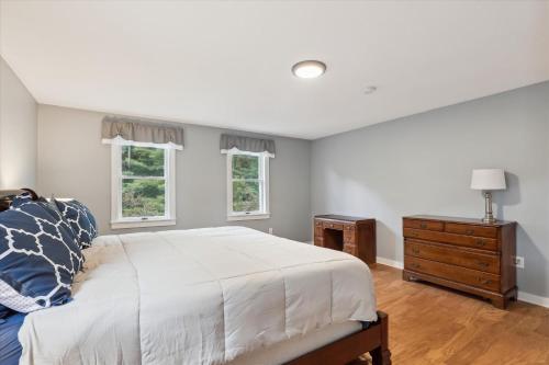 a bedroom with a bed and a dresser and two windows at Elmore Meadows in Stowe