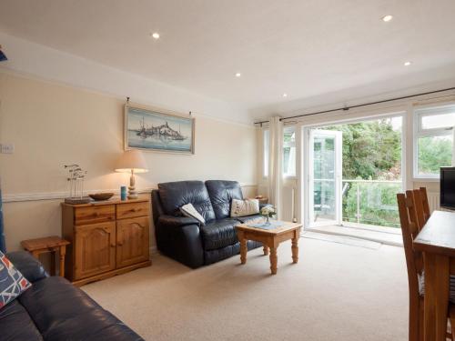 een woonkamer met een zwarte leren bank en een tafel bij St Elmo Lodge - Cottage in Salcombe