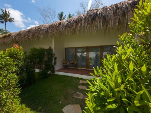 a house with a thatched roof and a yard at Terramar Villas in Kuta Lombok