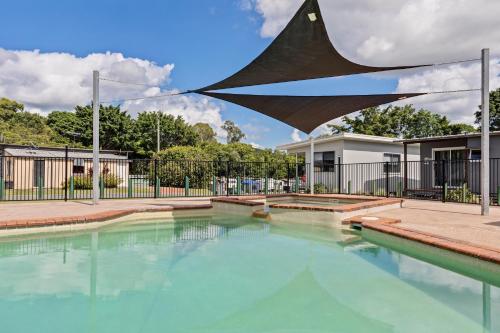 a swimming pool with a sculpture in front of a house at Yandina Caravan Park in Yandina