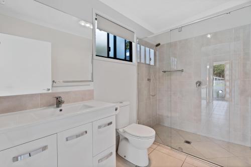 a white bathroom with a toilet and a shower at Yandina Caravan Park in Yandina