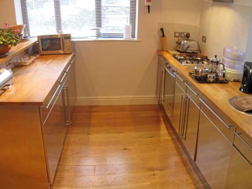 a kitchen with wooden counter tops and a microwave at Tick Tock Cottage in Baslow