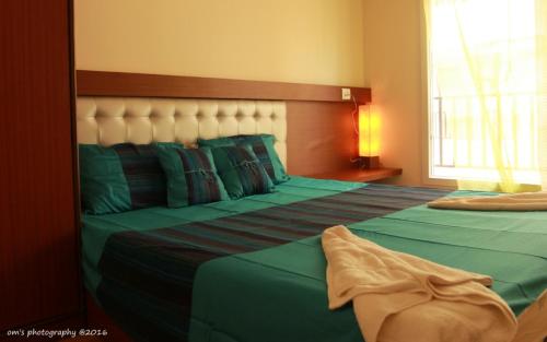 a bedroom with two beds with green sheets and a window at Goa Fiesta in Arpora