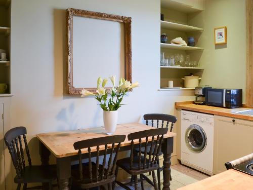 a kitchen with a table with chairs and a washing machine at Blackbird House in Alnwick