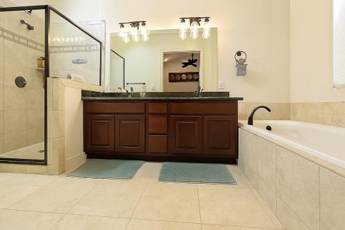 a bathroom with a sink and a tub and a mirror at Shop, Soak &Sleep Galleria 3BR Retreat Private Jacuzzi in Houston