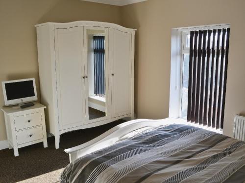 a bedroom with a bed and a tv on a dresser at Filey House in Sheringham