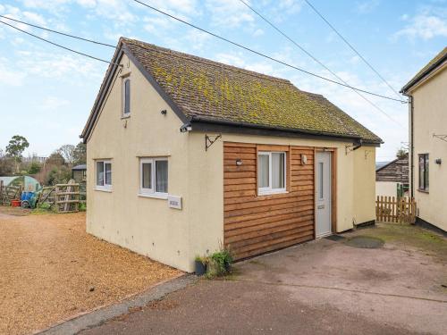 a small white house with a wooden garage at The Lodge in Pauntley