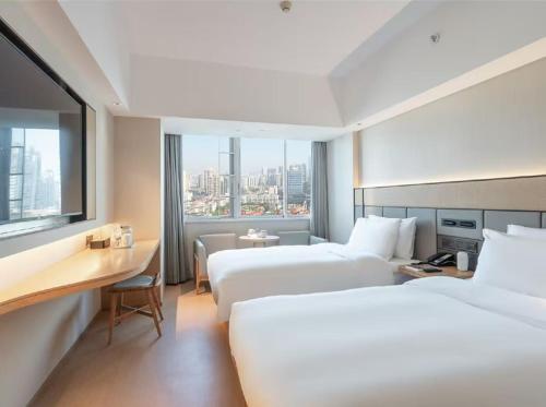 a hotel room with two beds and a desk at Ji Hotel Guangzhou Zhujiang New Town in Guangzhou