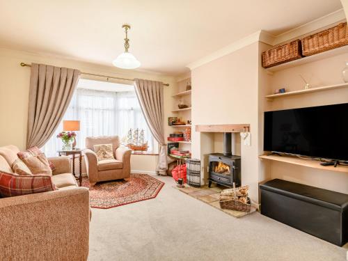 sala de estar con TV y chimenea en Woodland, en Sheringham