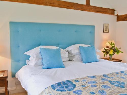 a bedroom with a large bed with a blue headboard at Priory Barn in Weald