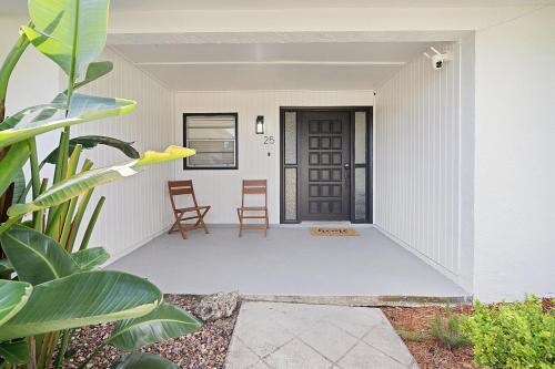 a porch of a house with two chairs and a door at Relaxing Coastal POOL Home 10 min to the Beach Pets stay free in Palm Coast