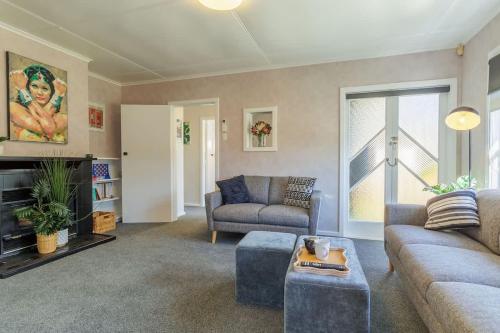 un salon avec un canapé et une cheminée dans l'établissement Cute on Konene - Quiet & Central Family ready, à Rotorua