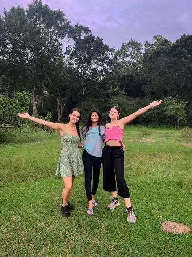 three girls standing in a field with their arms outstretched at Lake Front Yala Safari in Kataragama