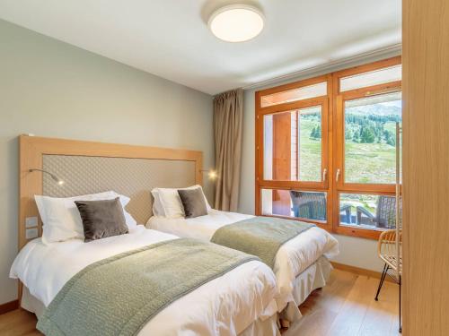 two beds in a hotel room with a window at Superbe 4 pièces moyen pour 6 pers. avec piscine, spa, fitness, parking couvert, ski aux pieds - FR-1-352-68 in Arc 1800