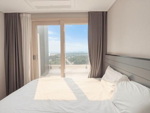 a bedroom with a large bed and a large window at Sokcho Whalejib The Blue Terra Ocean Stay in Puwŏl-li