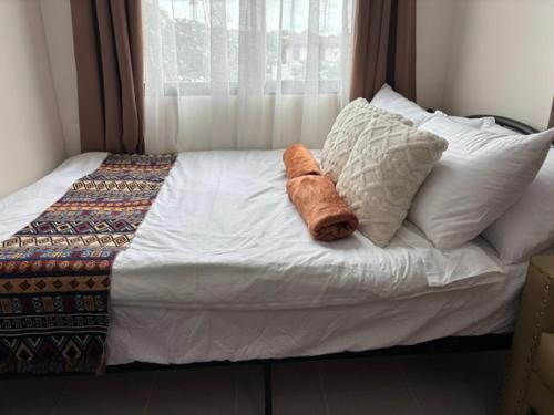a bed with white sheets and pillows and a window at Dainty Den LS217- Chic & Relaxing Stay Near Enchanted Kingdom in Santa Rosa