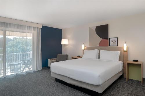 a hotel room with a large bed and a balcony at Spark by Hilton Chincoteague Island in Chincoteague