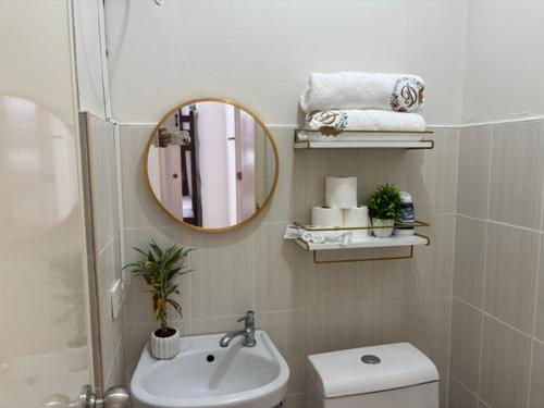 a bathroom with a sink and a mirror and a toilet at Dainty Den LS217- Chic & Relaxing Stay Near Enchanted Kingdom in Santa Rosa