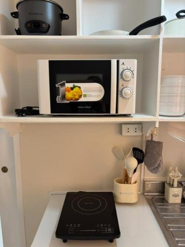 a microwave sitting on top of a kitchen counter at Dainty Den LS217- Chic & Relaxing Stay Near Enchanted Kingdom in Santa Rosa