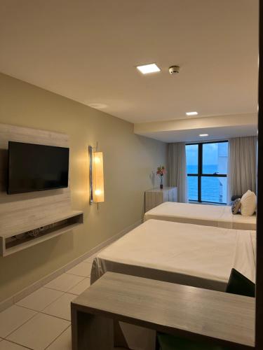 a hotel room with two beds and a flat screen tv at Seaside Refuge in Recife