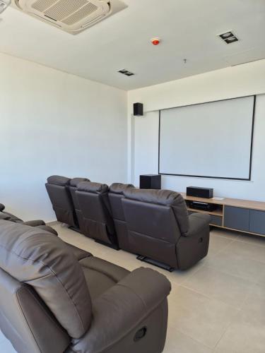 - un salon avec des fauteuils en cuir et un écran de projection dans l'établissement Molas Tower 14F, à Asuncion